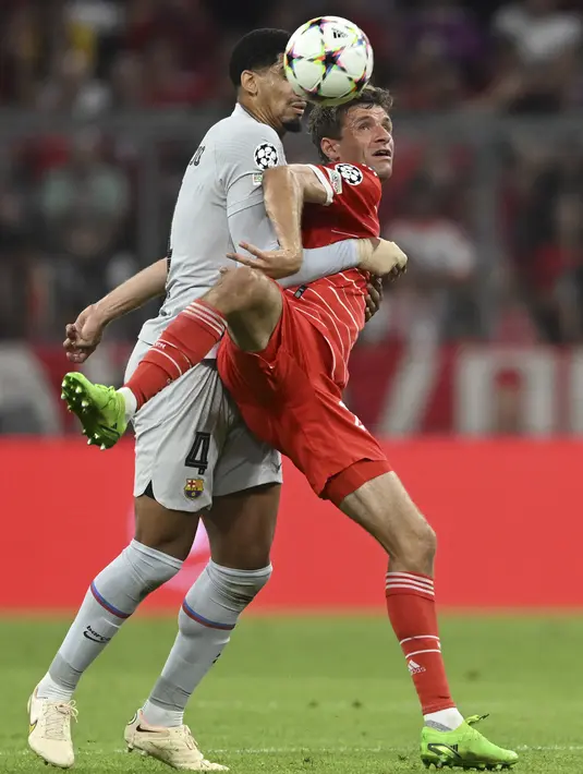 Penyerang Bayern Munchen Thomas Mueller berebut bola dengan bek Barcelona Ronald Araujo pada matchday 2 Grup C Liga Champions 2022/2023 di Allianz Arena, Rabu (14/9/2022) dini hari WIB. Barcelona takluk 0-2 saat dijamu Bayern Munchen. (AP Photo/Andreas Schaad)
