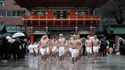 Penganut Shinto berjalan depan gerbang sebelum saat festival ketahanan dingin tahunan di Kuil Kanda Myojin Shinto, Tokyo, Jepang, Sabtu (18/1/2020). Menyiramkan air dingin ke tubuh diyakini dapat memurnikan jiwa mereka. (AP Photo/Eugene Hoshiko)