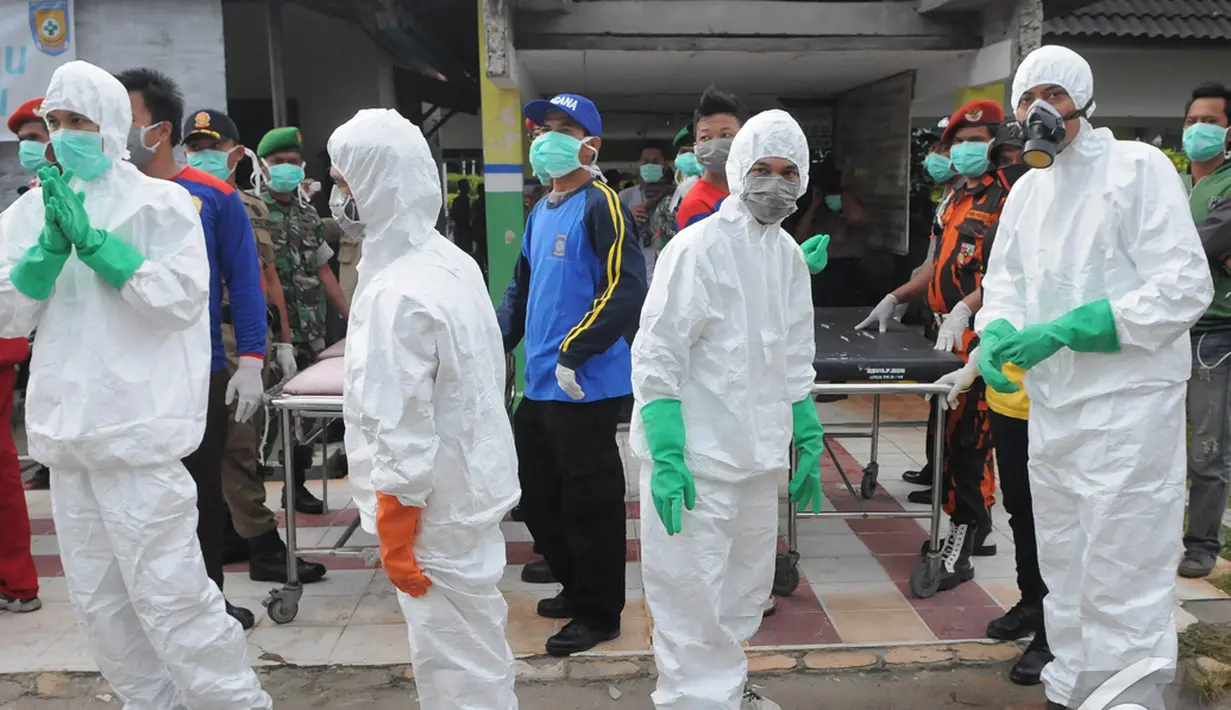 Relawan PMI bersiaga dengan mengenakan jas hujan putih, sarung tangan, dan masker, Pangkalan Bun, Kalteng, Senin (5/1/2015). (Liputan6.com/Herman Zakharia)