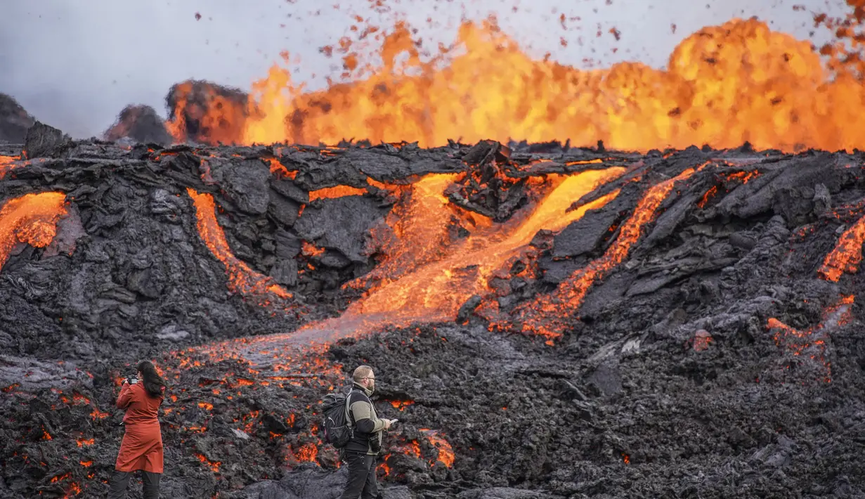 Orang-orang melihat lava yang mengalir di gunung berapi Fagradalsfjall di Islandia pada Rabu (3/8/2022), yang terletak 32 kilometer (20 mil) barat daya ibu kota Reykjavik dan dekat dengan Bandara Internasional Keflavik. Pihak berwenang di Islandia mengatakan gunung berapi di barat daya negara itu meletus hanya delapan bulan setelah letusan terakhirnya secara resmi berakhir. (AP Photo/Marco Di Marco)