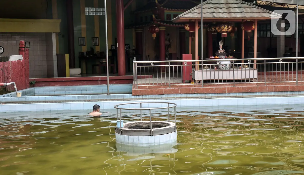 Warga keturunan Tionghoa berenang saat membersihkan diri di salah satu sumur Vihara Gayatri, Depok, Jawa Barat, Minggu (15/1/2023). (merdeka.com/Iqbal S. Nugroho)