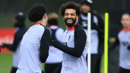 Striker Liverpool, Mohamed Salah bercanda dengan rekannya saat sesi latihan di AXA Training Centre, Liverpool (20/2/2023) menjelang menghadapi Real Madrid dalam laga leg pertama babak 16 besar Liga Champions 2022/2023. Mohamed Salah berpeluang membuat rekor sebagai top skor Liverpool di pentas Eropa jika mampu mencetak minimal satu gol ke gawang Real Madrid dalam laga dua leg. Saat ini Mohamed Salah duduk sejajar dengan legenda Liverpool, Steven Gerrard yang sama-sama mengemas total 41 gol di kancah Eropa. (AFP/Lindsey Parnaby)