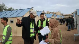 Pemilu ini digelar di tengah ketegangan yang tinggi dan kekhawatiran atas aneksasi wilayah oleh Israel. Tampak dalam foto, petugas pemilu Palestina menyiapkan Tempat Pemungutan Suara (TPS) darurat di tenda-tenda untuk pemilihan kota di Deir el-Balah, Jalur Gaza, pada Sabtu 25 April 2026. (Eyad Baba/AFP)