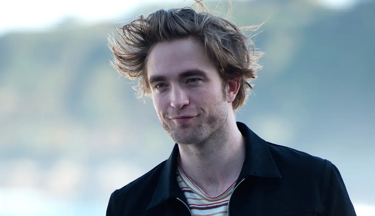 Aktor Inggris Robert Pattinson merapihkan rambutnya saat sesi pemotretan untuk mempromosikan filmn terbarunya "High Life" selama Festival Film San Sebastian ke-66, di kota Basque, San Sebastian, Spanyol utara (27/9). (AFP Photo/Ander Gillenea)