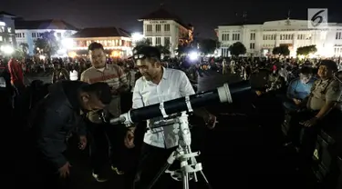 Warga menyaksikan gerhana bulan total lewat teleskop di Kota Tua Jakarta, Rabu (31/1). Selain menyediakan layar lebar, tiga unit teleskop disediakan untuk melihat fenomena super blue blood moon. (Liputan6.com/Arya Manggala)