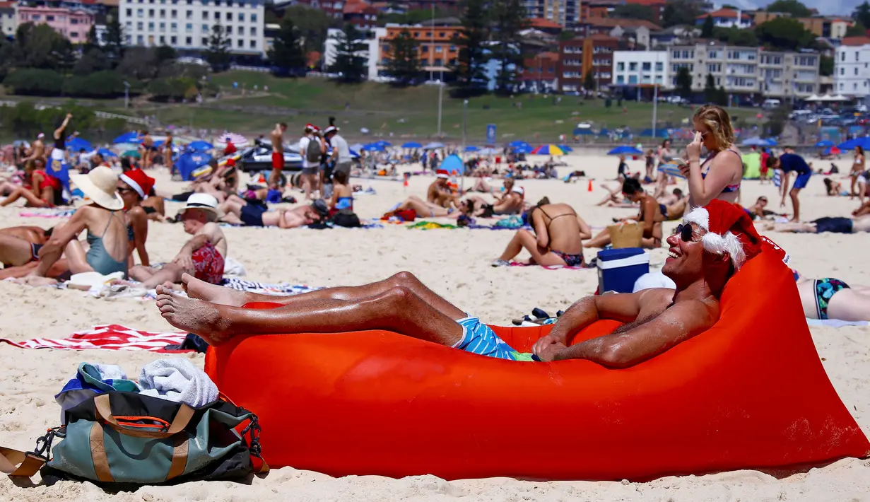 Seorang turis pria berjemur saat merayakan hari Natal di Bondi Beach Sydney pada Hari Natal di Australia, (25/12). (REUTERS/David Gray)