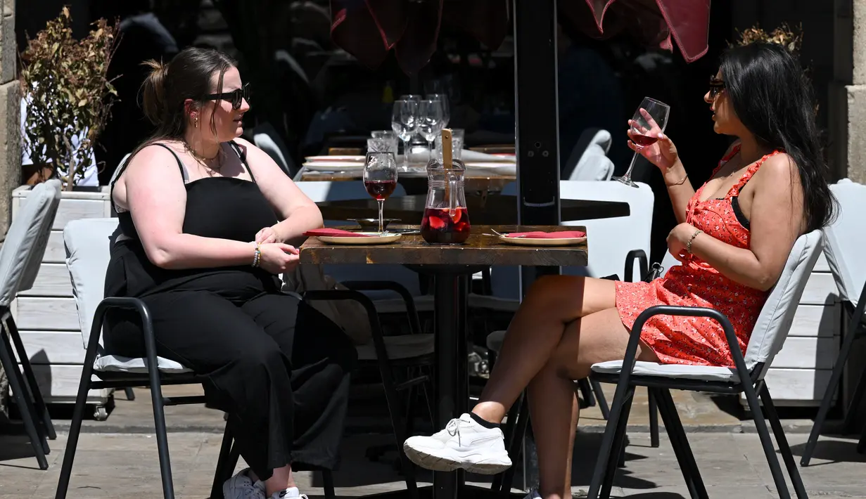 <p>Turis minum sangria di teras di Plaza Real di Barcelona, ​​​​pada 11 Mei 2022. Pengunjung sekali lagi memadati jalan-jalan sempit di kawasan Gothic Barcelona yang sempit saat perjalanan global bangkit kembali dari pandemi COVID-19, menghidupkan kembali kekhawatiran atas pariwisata massal di kota pelabuhan Spanyol. (LLUIS GEN / AFP)</p>