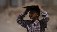 Seorang anak laki-laki yang kembali dari sekolah menutupi kepalanya dengan karton untuk melindungi dari sinar matahari pada hari yang panas di Jammu, India, Kamis (19/5/2022). Banyak bagian barat laut dan tengah India terus mengalami kondisi gelombang panas. (AP Photo/Channi Anand)