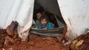 Anak-anak mengintip dari tenda pengungsian mereka yang kebanjiran di Kamp Cordoba, Batabu, Idlib, Suriah, Rabu (16/1). Banjir menggenangi tenda-tenda pengungsian mereka. (Aaref Watad/AFP)