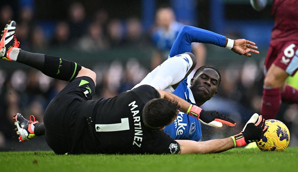 Kiper Aston Villa, Emiliano Martinez (kiri) berebut bola dengan pemain Everton, Amadou Onana pada laga lanjutan Liga Inggris 2023/2024 di Goodison Park, Liverpool, Inggris, Minggu (14/01/2024) malam WIB. (AFP/Paul Ellis)