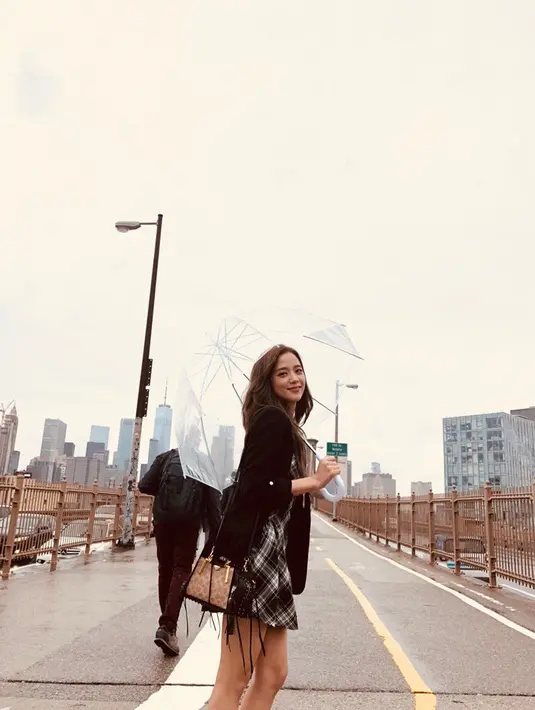 Jisoo juga tetap tampil elegan walaupun cuaca sedang tak bersahabat. Dengan gaya casual, Jisoo berpose di Brooklyn Bridge dengan membawa payung bening. (Liputan6.com/IG/@sooyaaa__)