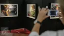 Pengunjung memotret karya foto yang dipajang pada pameran foto jurnalistik Setahun Kerja Jokowi-JK di Museum Bank Mandiri, Jakarta, Jumat (18/12). Pameran itu mengangkat berbagai kegiatan Kabinet Kerja selama setahun. (Liputan6.com/Faizal Fanani)