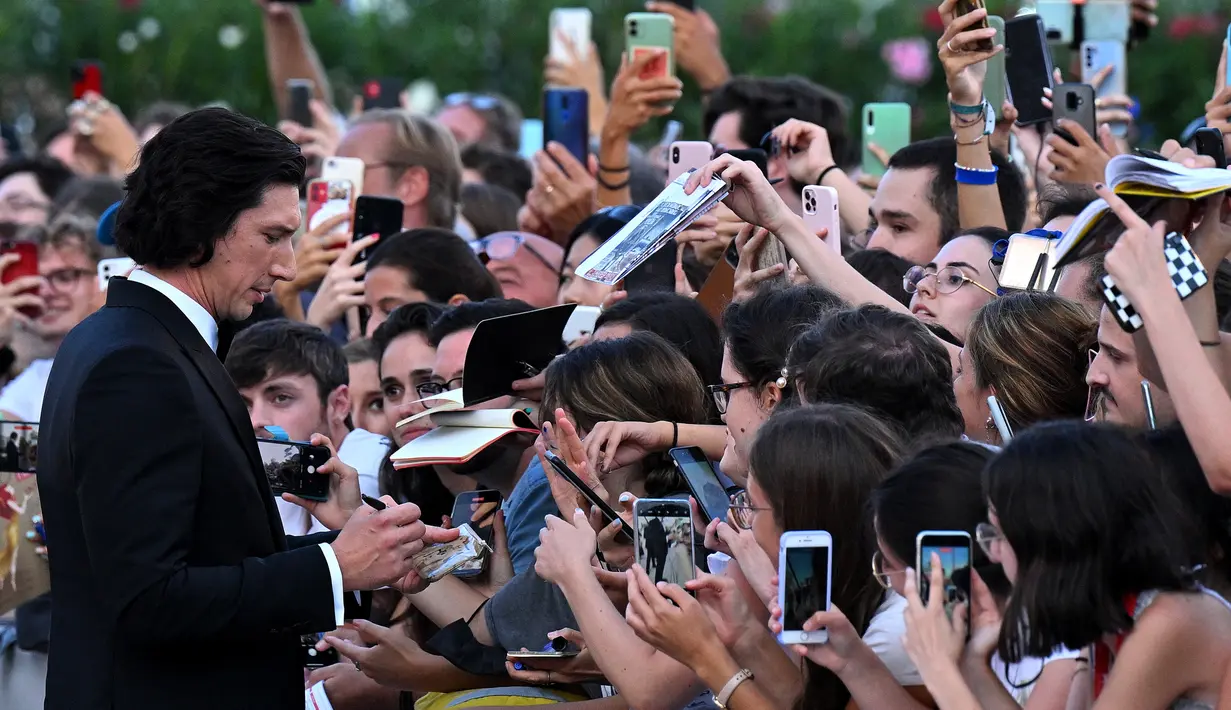 Aktor Amerika Serikat, Adam Driver menandatangani tanda tangan saat ia tiba untuk Upacara Pembukaan dan pemutaran film "White Noise" (31/8/2022) selama Festival Film Internasional Venesia ke-79 di Lido di Venezia di Venesia, Italia. Adam Driver dengan senang hati memberikan tanda tangannya pada para penggemar sambil berjalan di karpet merah pemutaran perdana White Noise selama Festival Film Venesia. (Tiziana FABI/AFP)