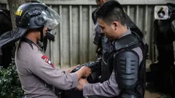 Personel Brimob bersiap mengenakan perlengkapan pelindung diri di Kawasan Bundaran HI, Jakarta, Selasa (13/10/2020). Sebanyak kurang lebih 12 ribu personel gabungan TNI, Polri dan Pemprov DKI Jakarta diterjunkan mengawal aksi tolak Undang-Undang Cipta Kerja Omnibus Law. (Liputan6.com/Faizal Fanani)