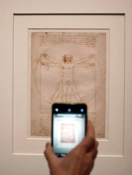 Awak media mengambil gambar "Vitruvian Man" karya Leonardo Da Vinci di museum Louvre, Paris, Selasa (22/10/2019). Louvre Paris, rumah Mona Lisa, menggelar pameran terbesar  Leonardo da Vinci memperingati 500 tahun wafatnya maestro Italia itu yang dibuka 24 Oktober mendatang (AP/Thibault Camus)