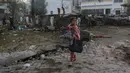 <p>Seorang gadis membawa selimut saat berjalan melewati lokasi ledakan mematikan di Rumah Sakit al-Ahli, Kota Gaza, Rabu (18/10/2023). (AP Photo/Abed Khaled)</p>