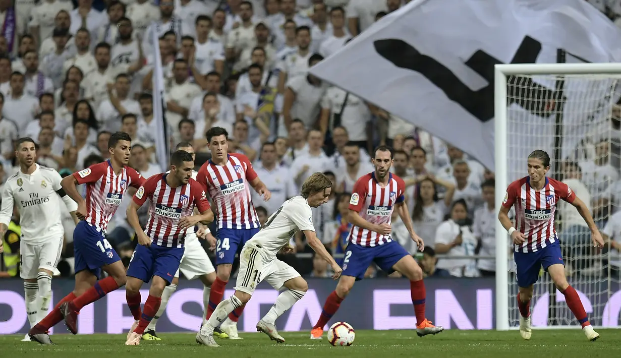 Gelandang Real Madrid, Luka Modric, berusaha melewati kepungan pemain Atletico Madrid pada laga La liga di Stadion Santiago Bernabeu, Madrid, Sabtu (29/9/2018). Kedua klub bermain imbang 0-0. (AFP/Oscar Del Pozo)