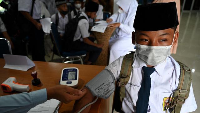 Seorang siswa sekolah menengah pertama menjalani pemeriksaan tekanan darah sebelum menerima dosis vaksin Sinovac pada acara vaksinasi virus corona COVID-19 di Blang Bintang, Provinsi Aceh, 21 September 2021. (CHAIDEER MAHYUDDIN/AFP)