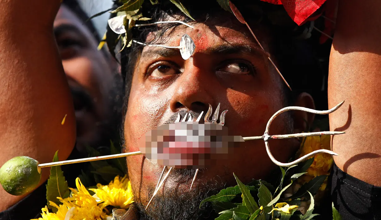 Seorang umat Hindu menusukkan besi ke pipi dan lidahnya saat Festival Thaipusam di Batu Caves, Kuala Lumpur, Malaysia, Rabu (31/1). Thaipusam merupakan perayaan untuk menghormati tuhan Hindu, Lord Murugan. (AP Photo/Sadiq Asyraf)