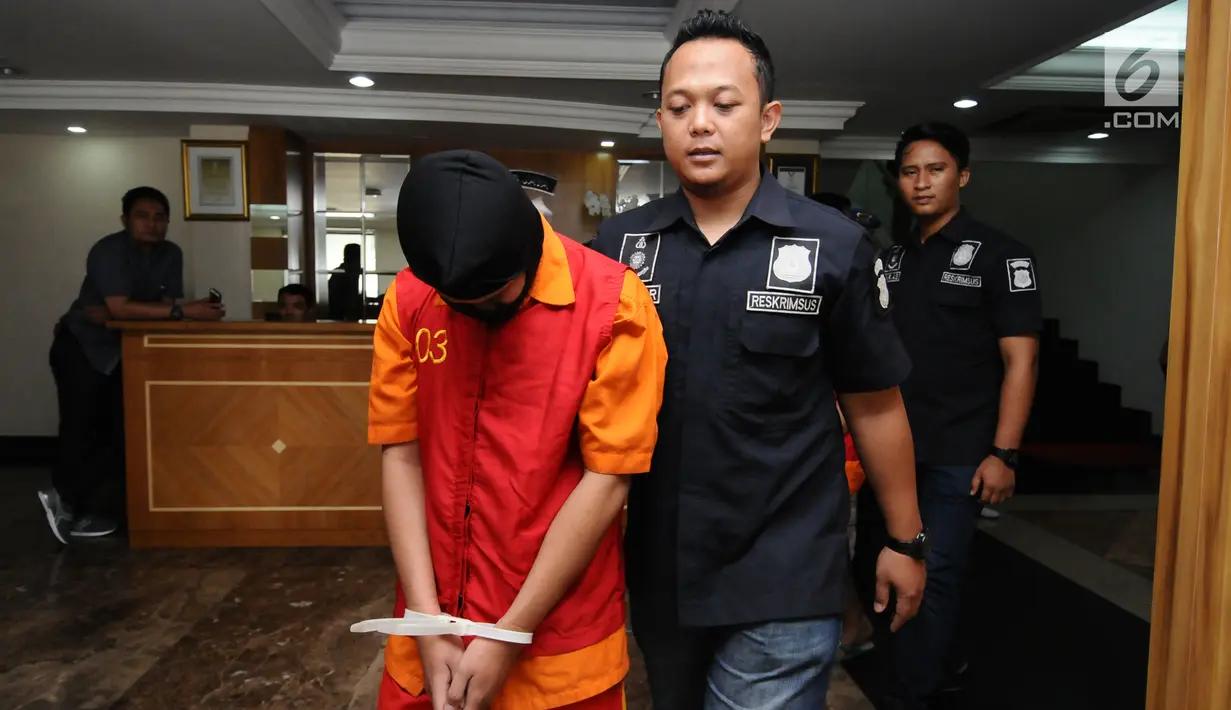 Petugas menggiring salah satu tersangka kasus pornografi berbasis media sosial di Mapolda Metro Jaya, Minggu (17/9). Para tersangka ini diduga berafiliasi dengan para pelaku kejahatan seksual anak dari berbagai negara. (Liputan6.com/Helmi Fithriansyah)