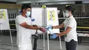 Petugas membersihkan tangan pemilih usai dia memberikan suaranya dalam pemilu di TPS Sekolah Tinggi Chung Cheng, Singapura, Jumat (10/7/2020). Pemilu di tengah pandemi COVID-19, warga Singapura memberikan suara mereka dengan mengenakan masker dan sarung tangan plastik. (AP Photo)