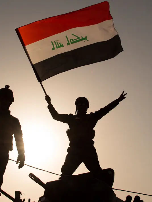 Anggota polisi Federal mengibarkan bendera nasional Irak saat merayakan keberhasilan mereka menyingkirkan militan ISIS dari Kota Tua Mosul, Minggu (9/7). Pada 2017 Mosul menjadi salah satu benteng terakhir militan ISIS. (FADEL SENNA/AFP)