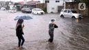 Warga melintasi banjir di jalan Bayangkara Pusdiklat, Kota Tangerang Selatan, Banten, Selasa (2/11/2021). BMKG mengeluarkan peringatan potensi cuaca ekstrem di wilayah Jakarta, Bogor, Depok, Tangerang, dan Bekasi (Jabodetabek). (Liputan6.com/Angga Yuniar)