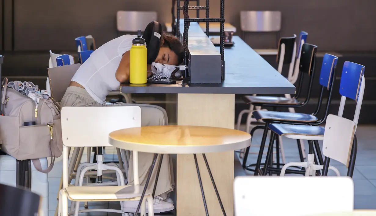 Seorang wanita tidur di meja stasiun pengisian di ruang keberangkatan bandara internasional Brussels selama pemogokan nasional di Brussels, Belgia, Senin (20/6/2022). Semua keberangkatan keluar dari bandara dibatalkan pada hari Senin setelah pemogokan nasional terhadap biaya hidup dan upah terjadi di Belgia. (AP Photo/Olivier Matthys)
