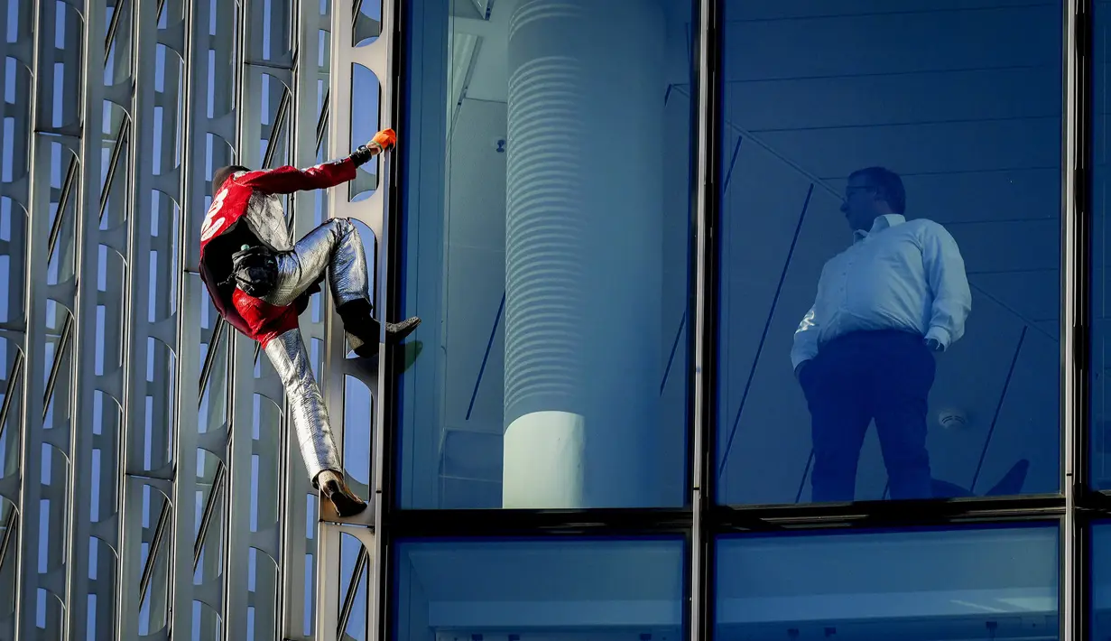 Alain Robert yang dikenal sebagai 'Spiderman Prancis' (kiri) memanjat gedung pencakar langit Skyper di pusat Frankfurt, Jerman, 23 November 2021. Alain Robert memanjat gedung setinggi 153 meter itu untuk meningkatkan kesadaran dunia tentang masalah perubahan iklim. (AP Photo/Michael Probst)