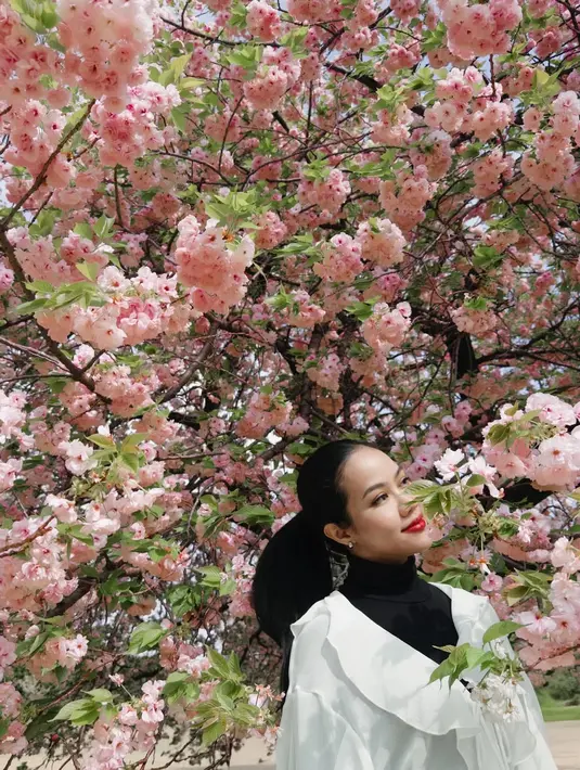 Aura feminin dan elegan terpancar dari gaya busananya. Ia mengenakan blouse putih dengan aksen ruffle dramatis di bagian dada dan lengan yang mengembang. [@yurayunita].