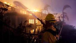 Seorang petugas pemadam kebakaran bekerja untuk memadamkan sebuah bangunan yang terbakar saat kebakaran hutan di Laguna Niguel, California, Amerika Serikat, 11 Mei 2022. (AP Photo/Marcio J. Sanchez)