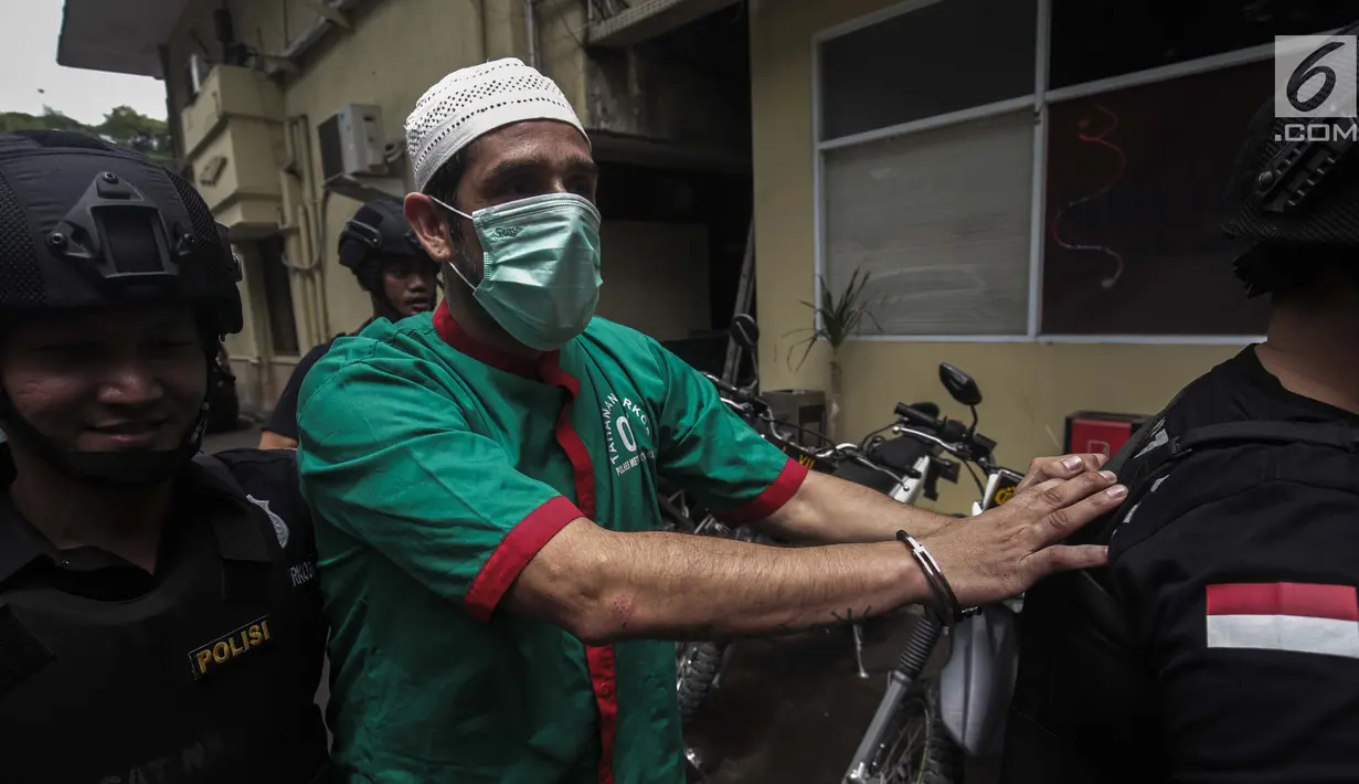Artis Claudio Martinez memakai masker dengan tangan di borgol usai rilis narkoba di Polres Jakarta Barat, Jumat (9/11). Claudio ditangkap dengan barang bukti 7,96 gram ganja. (Liputan6.com/Faizal Fanani)