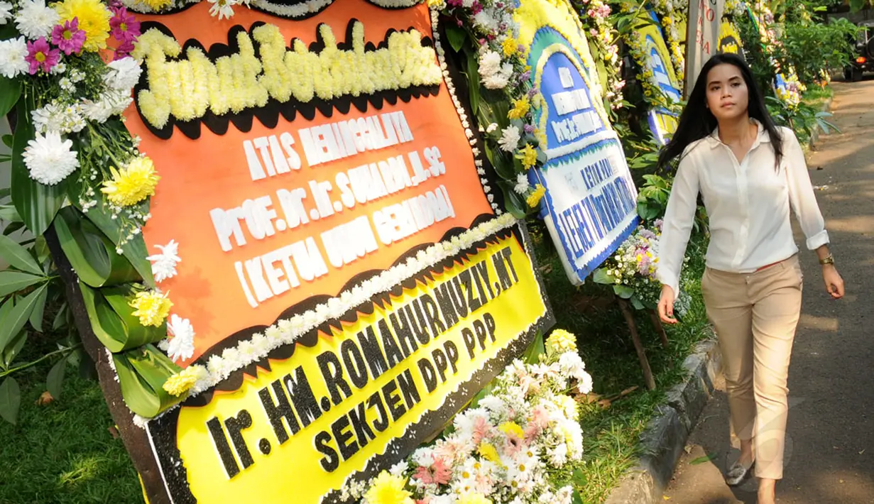 Seorang perempuan berjalan melintasi karangan bunga di pelataran kantor DPP Partai Gerindra, tempat disemayamkannya Alm Suhardi, (29/8/2014). (Liputan6.com/Helmi Fithriansyah)