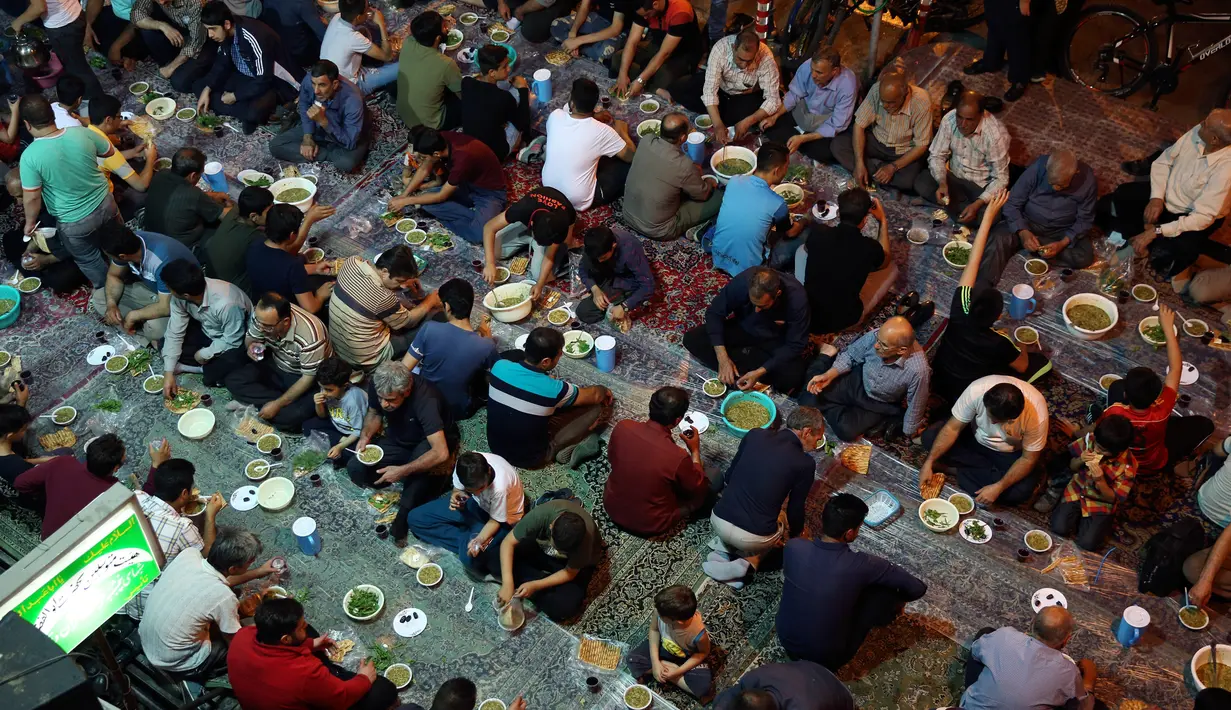 Warga muslim Iran berkumpul untuk berbuka puasa bersama di sebuah jalan di Teheran, 29 Mei 2018. Mereka yang sedang berpuasa dan berada jauh dari tempat tinggalnya mengikuti tradisi buka bersama di jalanan. (AP Photo/Vahid Salemi)