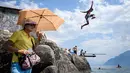 <p>Turis menggunakan payung berada di Danau Jenewa di Saint Saphorin, Swiss barat saat gelombang panas melanda seluruh Eropa utara (31/7). Wilayah yang terkena dampak gelombang panas Valais, Danau Jenewa, Ticino dan Basel. (AFP Photo/Fabrice Coffrini)</p>