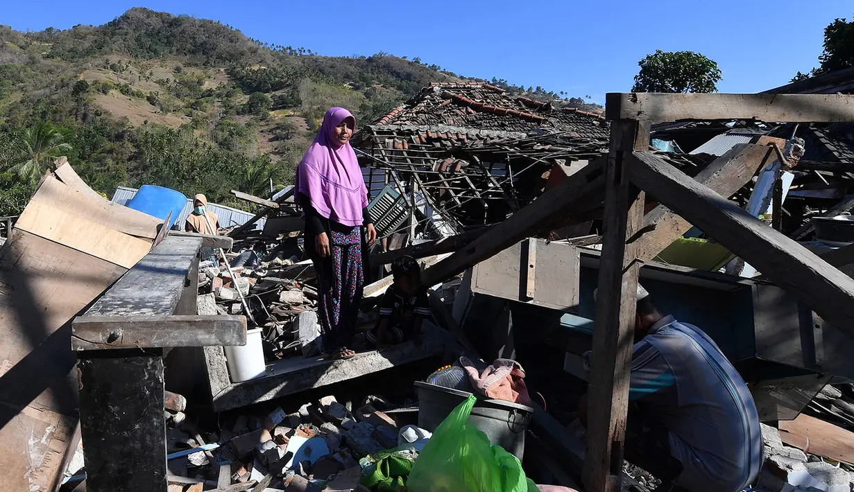 Seorang perempuan mencari sisa-sisa puing dari bangunan rumah yang rusak di Menggala, Lombok Utara, Rabu (8/8). Laporan terakhir mengatakan, gempa Lombok telah memakan 105 korban jiwa, dan lebih 70.000 orang kehilangan tempat tinggal. (AFP/ADEK BERRY)