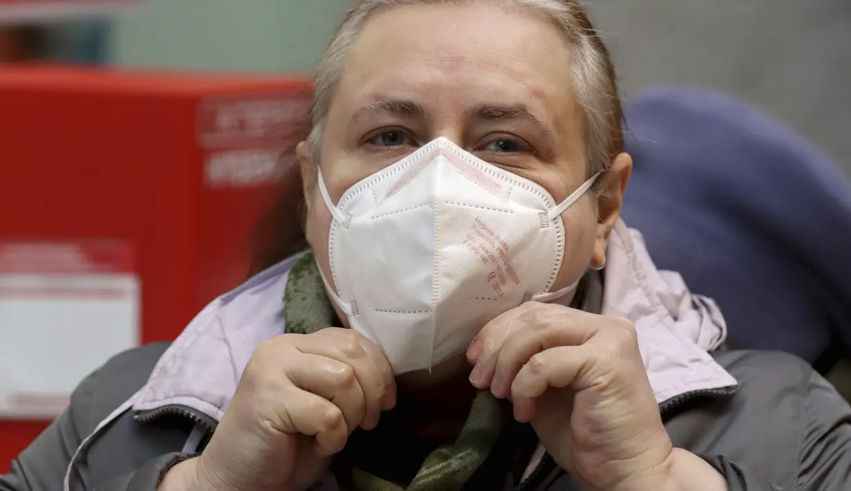 Seorang perempuan menyesuaikan masker FFP2 jenis respirator saat berbelanja di supermarket di Wina, Austria, Senin (25/1/2021). Mulai 25 Januari 2021, warga Austria diwajibkan mengenakan masker FFP2 di supermarket, apotek, pompa bensin, dan di transportasi umum. (AP Photo/Ronald Zak)
