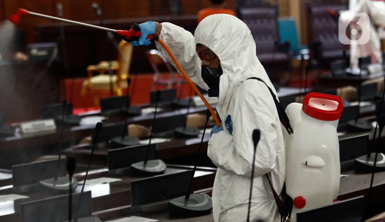 Petugas melakukan penyemprotan cairan disinfektan di area ruang rapat paripurna di Gedung Nusantara, Kompleks Parlemen MPR/DPR-DPD, Senayan, Jakarta, Minggu (29/3/2020). Penyemprotan ini dilakukan karena akan digelar rapat paripurna pada hari Senin, 30 Maret 2020. (Liputan6.com/Johan Tallo)