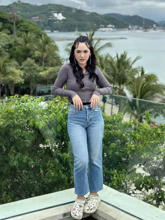 Berfoto dengan pemandangan pantai, Happy Asmara tampil dengan cardigan dipadukan celana denim serta sandal karetnya.  (@happy_asmara77)