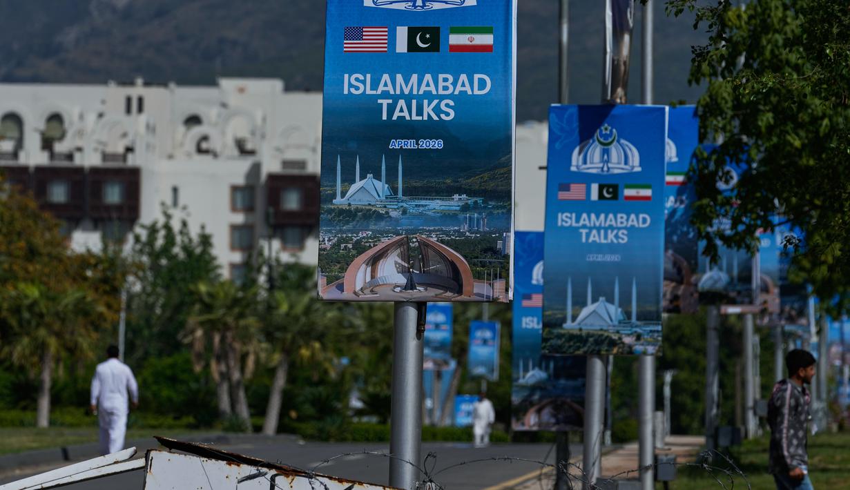 Para pekerja berjalan melewati papan reklame di dekat Hotel Serena, menjelang putaran kedua negosiasi antara Amerika Serikat dan Iran, di Islamabad, Pakistan, Senin 20 April 2026. Hari ini, Senin 20 April 2026, Iran secara resmi menyatakan menolak mengirimkan delegasi untuk melanjutkan perundingan damai tahap dua dengan Amerika Serikat (AS) di Islamabad, Pakistan. (AP Photo/Anjum Naveed)