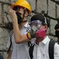 Para siswa sekolah mengenakan topeng dan helm berjalan di luar St. Paul's College selama protes di Hong Kong, Selasa (3/9/2019). Puluhan ribu siswa di Hong Kong memprotes terhadap gerakan anti-pemerintah. (AP Photo/Kin Cheung)