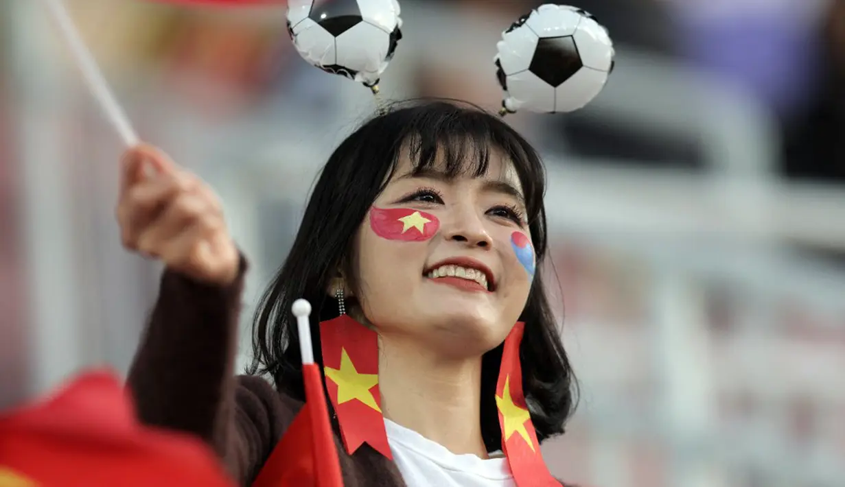 Suporter Timnas Indonesia dan Vietnam sama-sama mengenakan aksesoris senada dengan warna bendera negara mereka saat menyaksikan timnya bertanding. (KARIM JAAFAR/AFP)