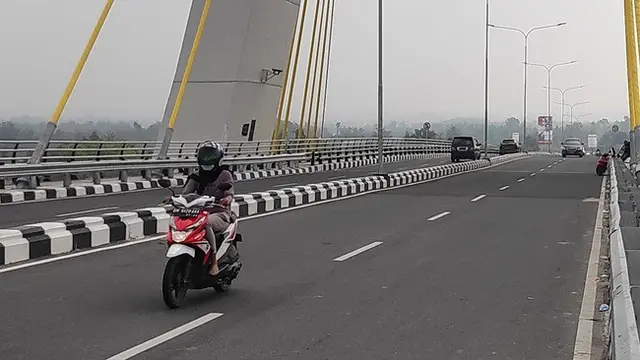 Pengendara sepeda motor di Pekanbaru memakai masker karena kabut asap dari kebakaran lahan.