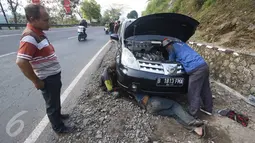 Pemilik mobil memperhatikan mobilnya yang tengah diperbaiki oleh montir di Jalan Warung Peuteuy, Garut, Jabar, Senin (4/7). Banyaknya kendaraan pemudik yang rusak menjadi berkah bagi para montir panggilan. (Liputan6.com/Immanuel Antonius)