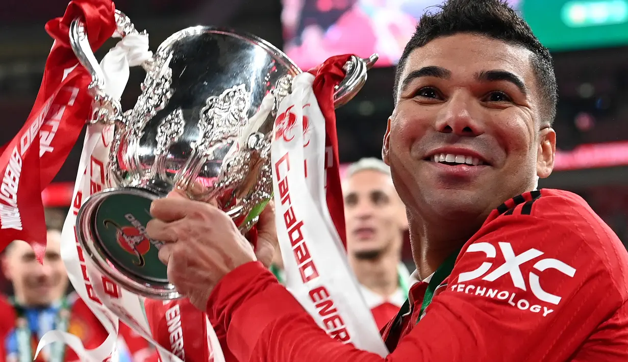 Gelandang Manchester United, Casemiro memegang trofi Carabao Cup 2022/2023 selama perayaan juara usai mengalahkan Newcastle United pada laga final di Stadion Wembley di London, Senin dini hari WIB (27/2/2023). Casemiro juga berperan besar membantu pertahanan dengan 5 tekel bersih dan 58% umpan sukses. (AFP/GLYN KIRK)