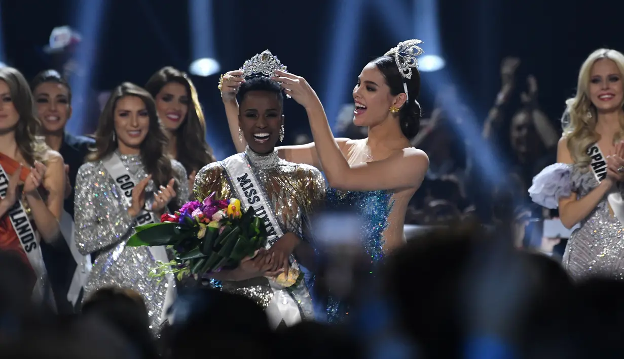 Miss Universe 2018 Catriona Grey menyematkan mahkota kepada Miss Afrika Selatan, Zozibini Tunzi, seusai dinobatkan menjadi Miss Universe 2019 pada malam final di Tyler Perry Studios, Atlanta, Minggu (8/12/2019). Zozibini Tunzi, 26, dinobatkan menjadi Miss Universe 2019. (VALERIE MACON / AFP)