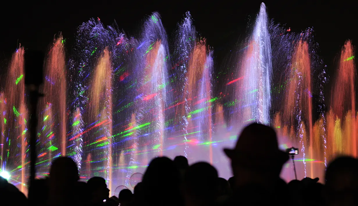 Pengunjung menyaksikan air mancur menari pada awal musim semi di taman Warsawa, Polandia, 1 Mei 2018. Atraksi ini memadukan teknologi pertunjukan lampu laser tiga dimensi, semburan menara api, layar air digital serta pancuran air. (AP/Alik Keplicz)