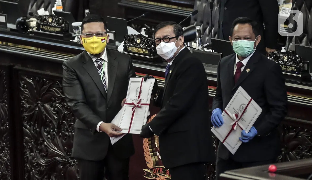 Ketua Komisi II Ahmad Doli Kurnia (kiri) memberikan salinan Perppu kepada Menkumham Yasonna Laoly dan Mendagri Tito Karnavian usai Rapat Paripurna ke-18 Masa Persidangan IV 2019-2020 di Kompleks Parlemen, Jakarta, Selasa (14/7/2020). Perppu Pilkada disahkan menjadi UU. (Liputan6.com/Johan Tallo)
