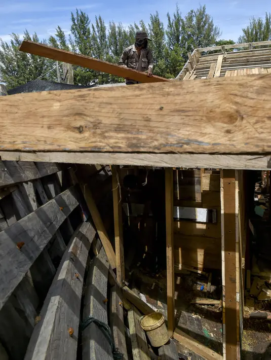 Pekerja memuat material untuk membuat kapal nelayan di Banda Aceh, Aceh pada 21 November 2020. Industri galangan kapal tradisional di daerah itu mengalami kesulitan memperoleh bahan baku kayu untuk memproduksi kapal nelayan, sehingga berdampak pada proses penyelesaian kapal. (CHAIDEER MAHYUDDIN/AFP)