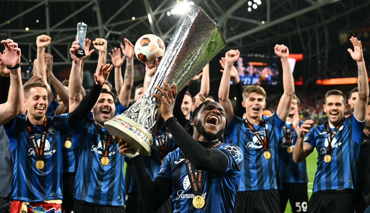 Pemain Atalanta, Ademola Lookman mengangkat trofi Liga Europa setelah timnya mengalahkan Bayer Leverkusen pada laga final yang berlangsung di Dublin Arena, Irlandia, Kamis (23/05/2024) dini hari WIB. Lookman berhasil mencetak hattrick dan membawa Atalanta menang dengan skor 3-0. (AFP/Ben Stansall)